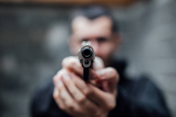 A man is pointing a gun directly at the lens.